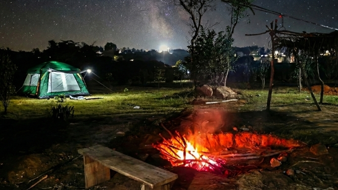 Night camping scene with a glowing tent,